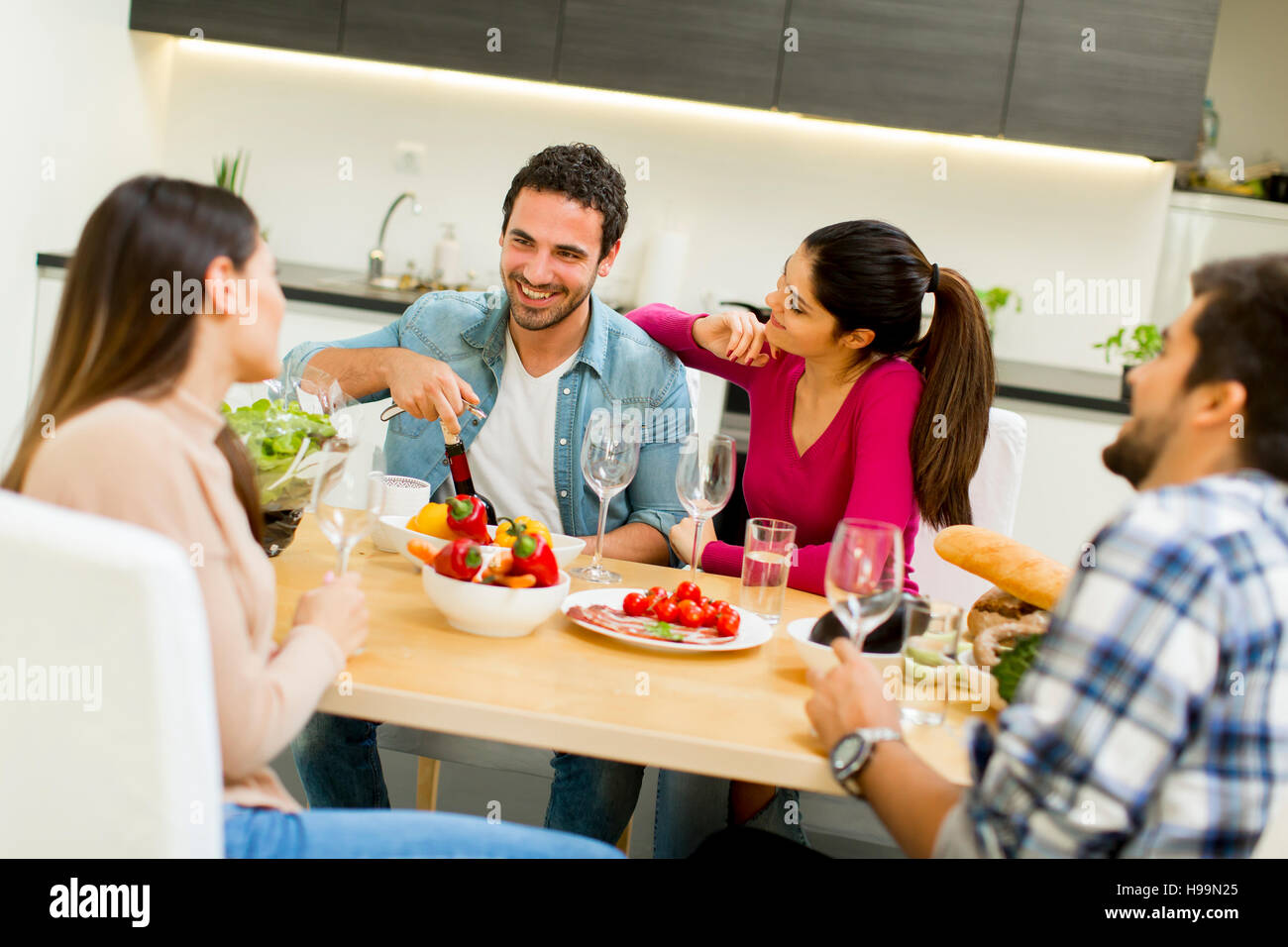 Group of happ young people sitting by the table eating and drinking red wine Stock Photo Alamy