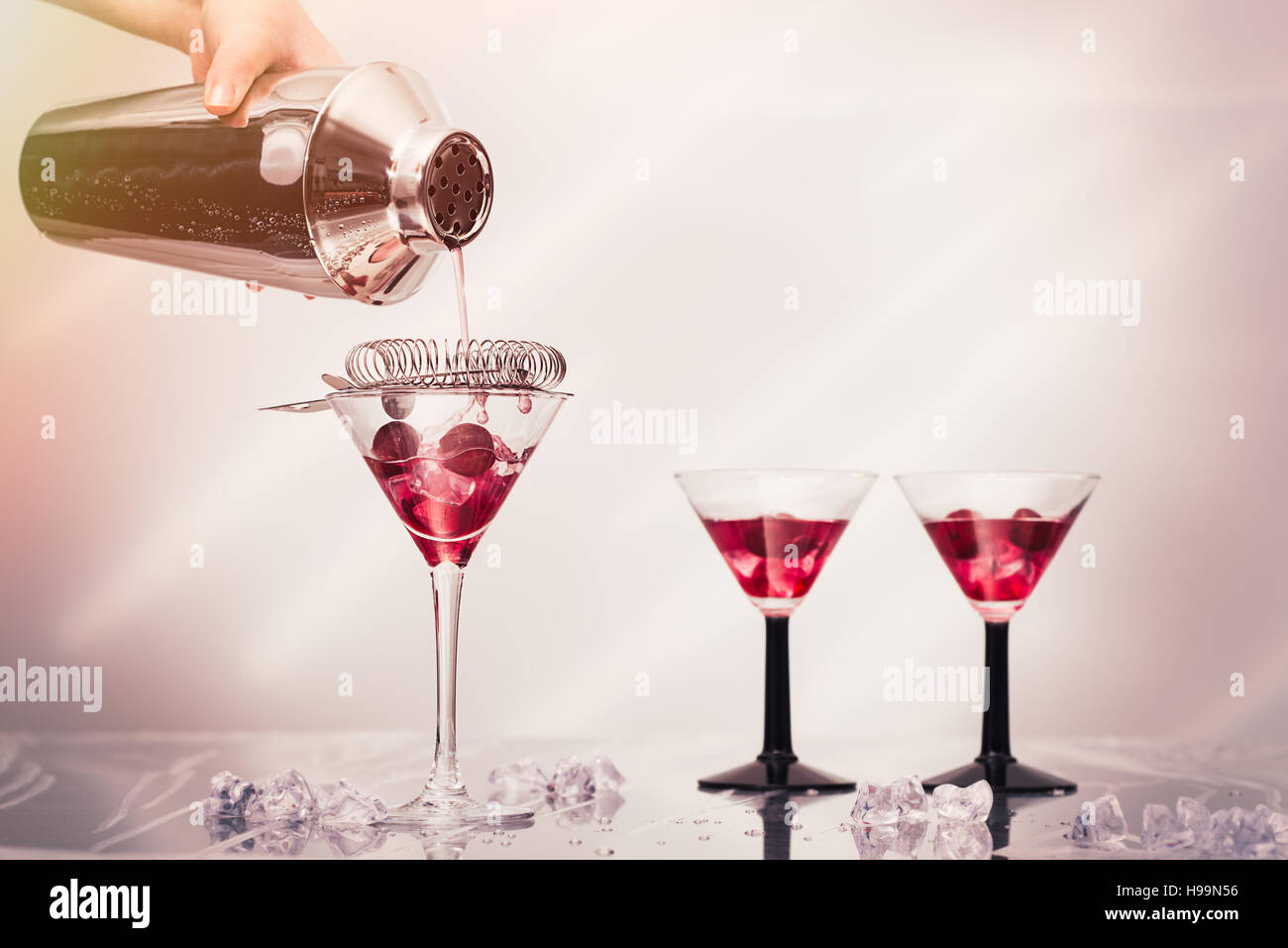 Pouring cocktail drink from a shaker into Art Deco cocktail glasses