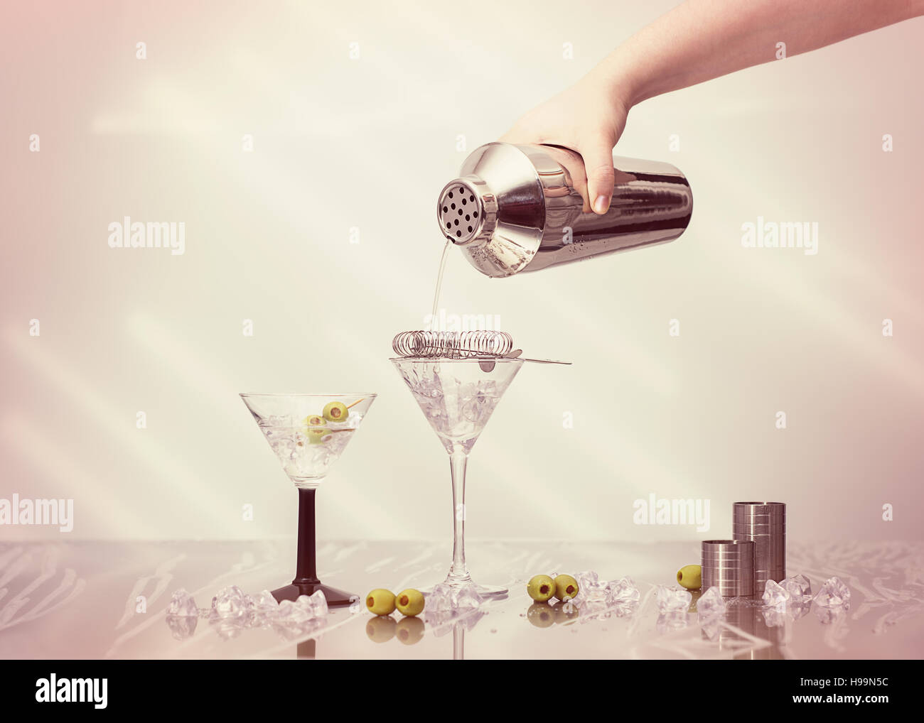 Pouring cocktail drink from a shaker into Art Deco cocktail glasses