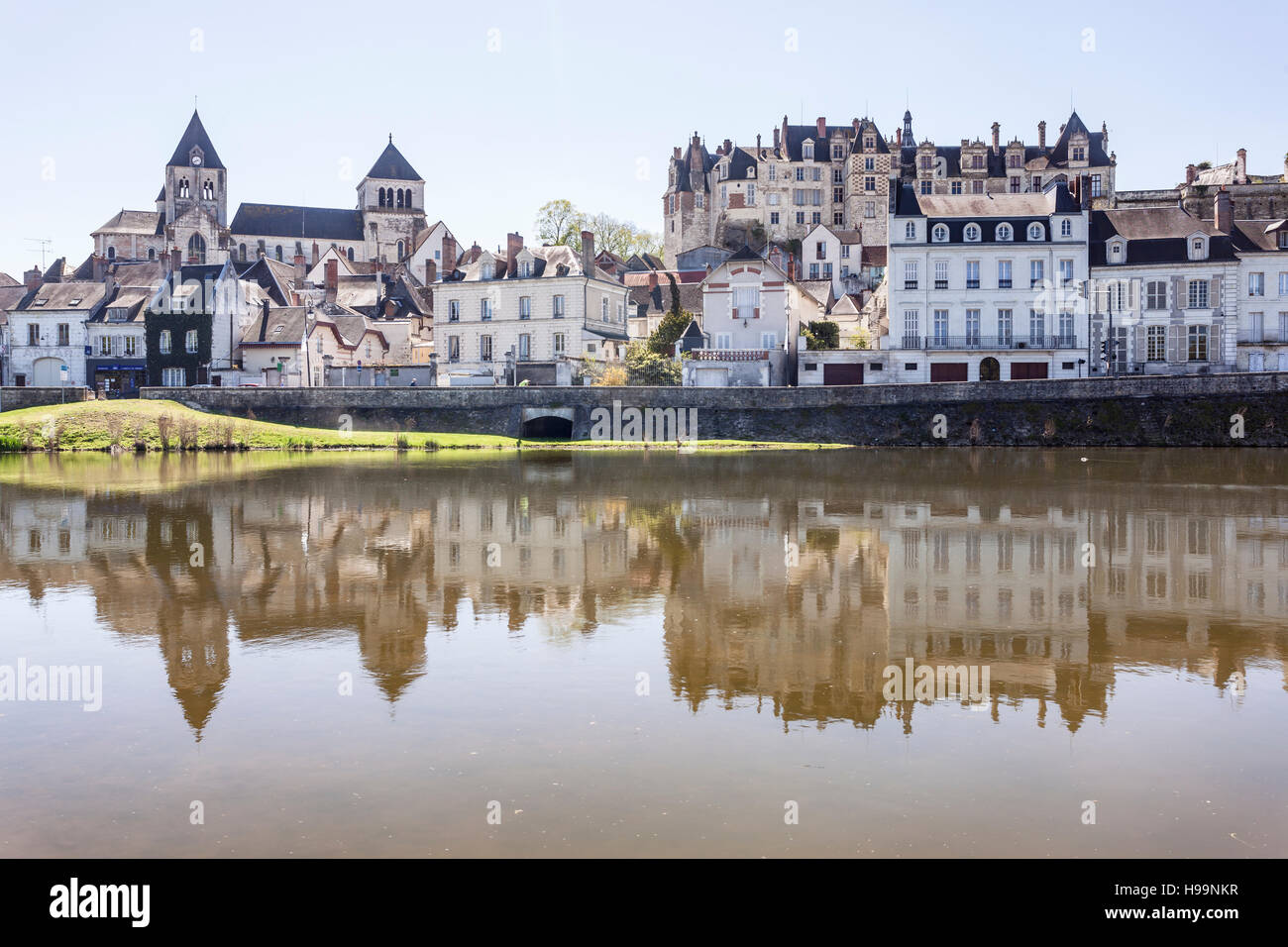 The small town of Saint Aignan reflecting in the river Cher on a hot spring day. The chateau can be seen looming over the town below. Stock Photo