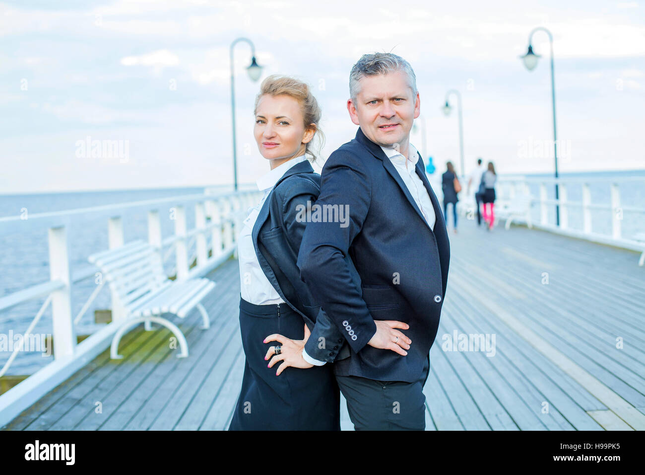 Two business people on jetty with hands on hips Stock Photo