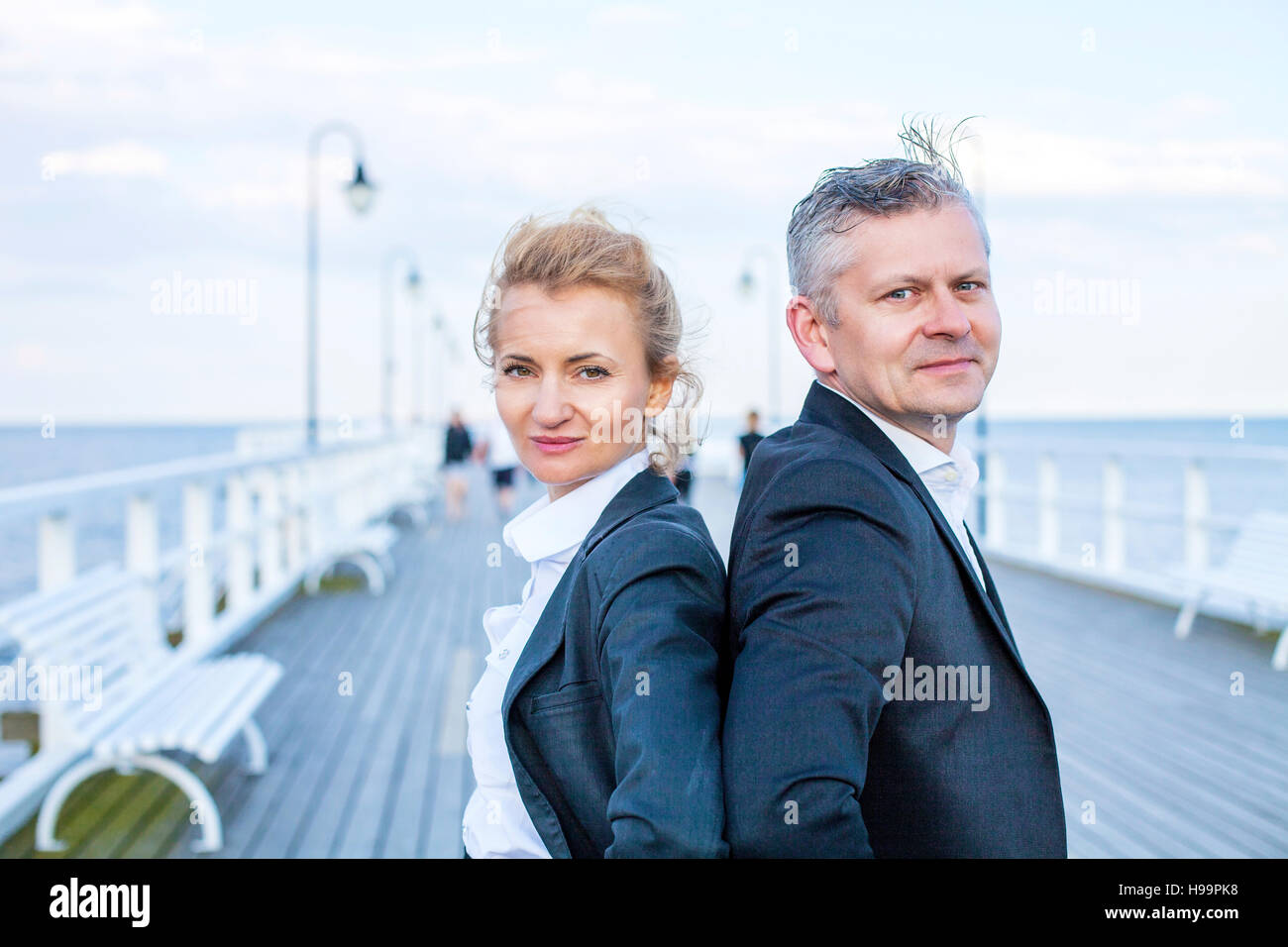 Two business people on jetty with hands on hips Stock Photo