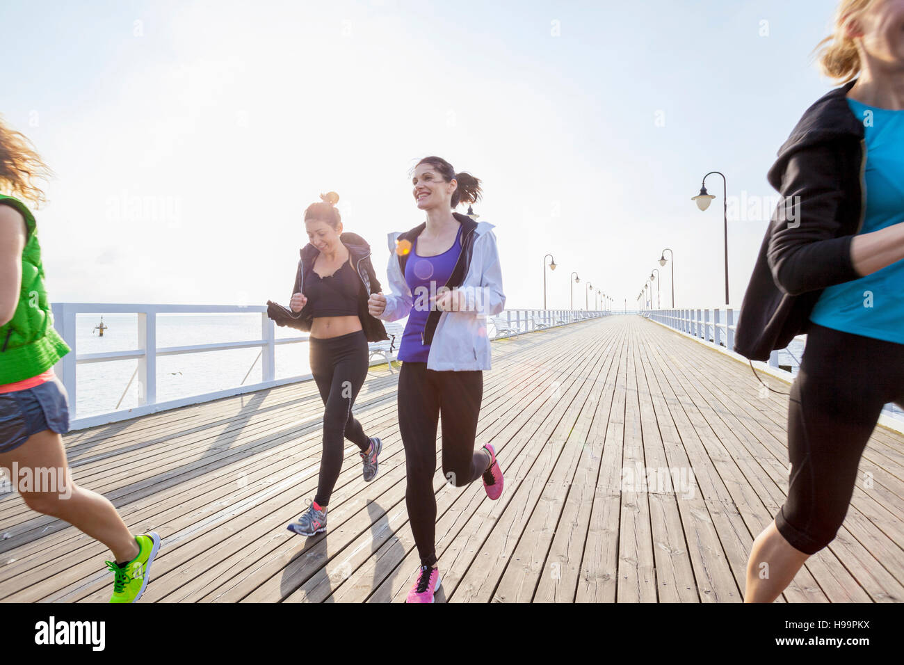 Group of women in sports clothing running on jetty Stock Photo
