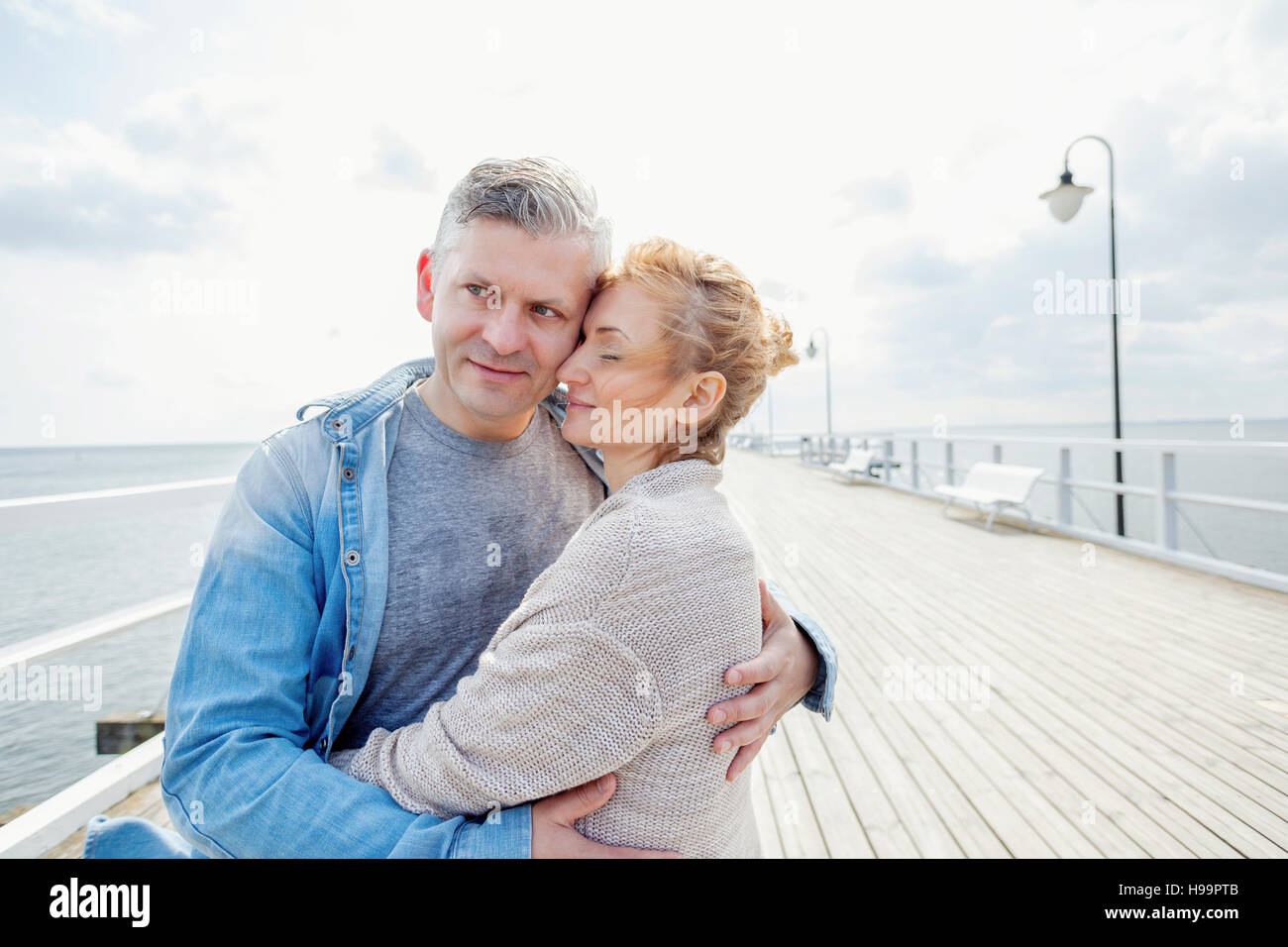 Couple on jetty embracing Stock Photo