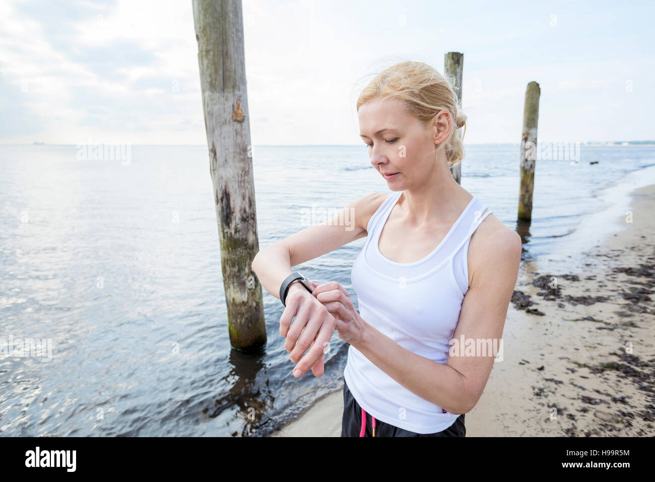 Woman on beach checking running watch Stock Photo