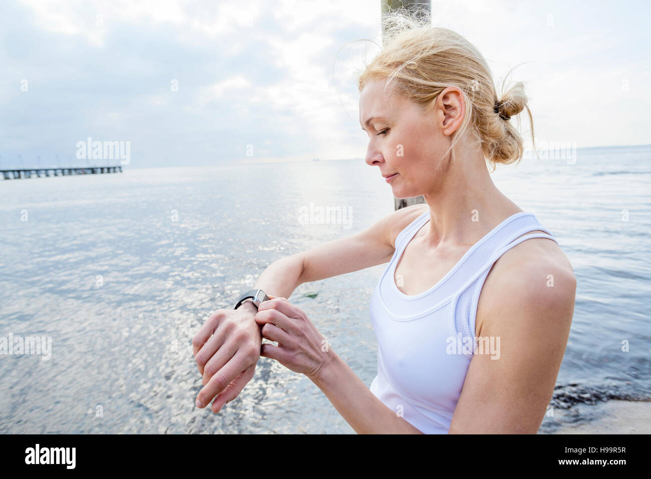 Woman on beach checking running watch Stock Photo