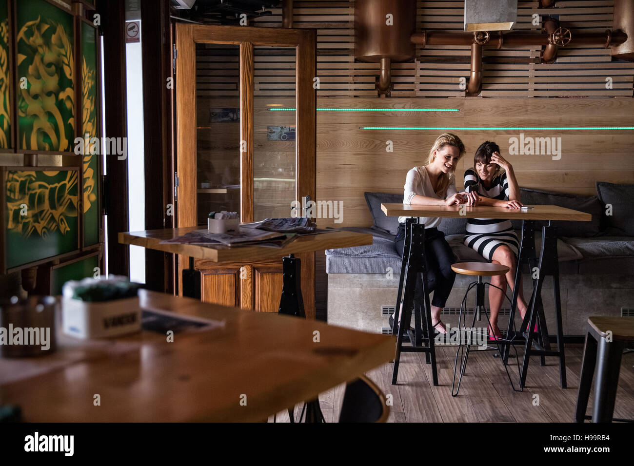 Two women in coffee shop using their smartphones Stock Photo