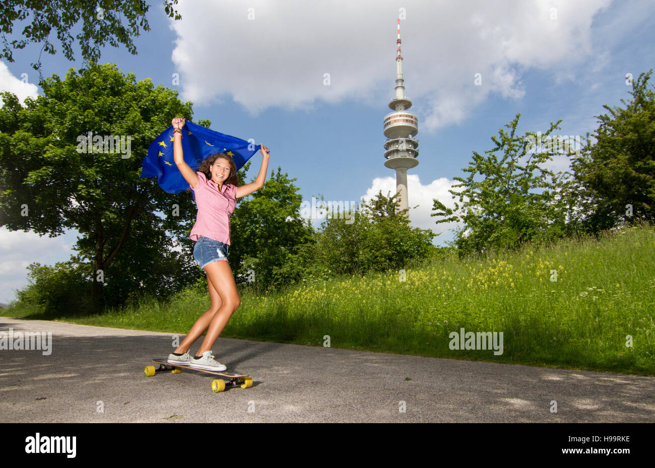 Young woman holds European flag while skateboarding Stock Photo