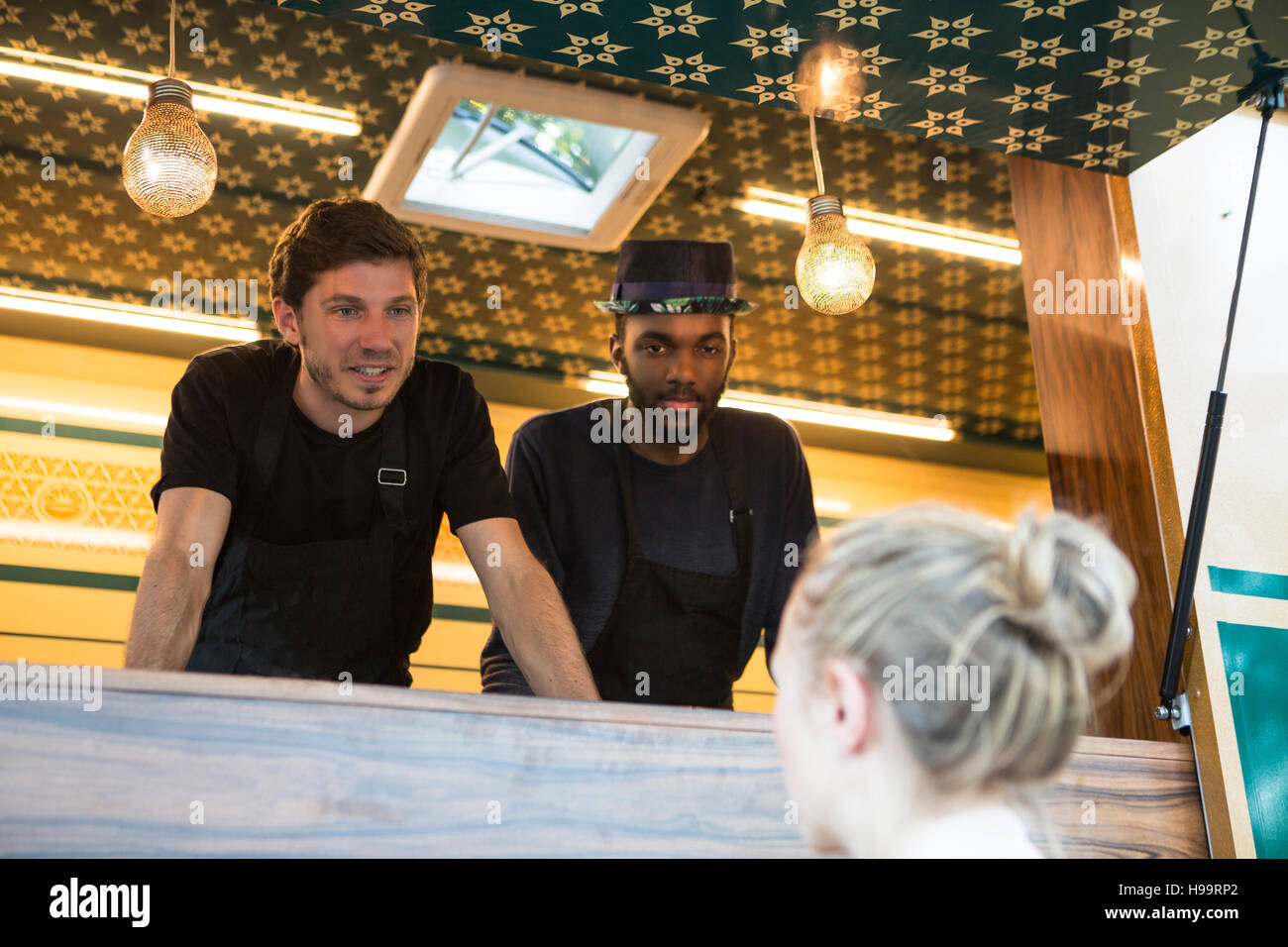 Food truck vendors talking to female customer Stock Photo