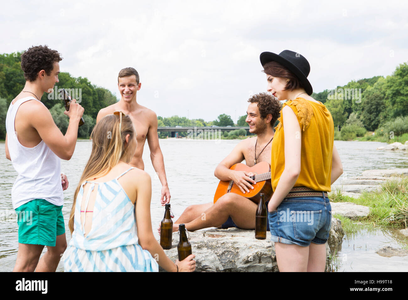 Group of friends drinking beer on the riverbank Stock Photo