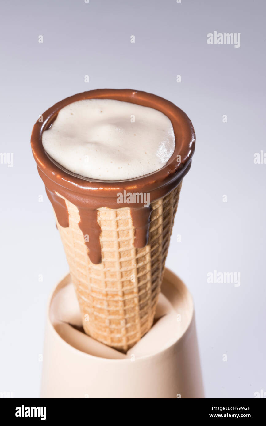 Coffee in waffle cone dipped in chocolate with drawings in cappuccino / latte milk foam, latte art, isolated Stock Photo