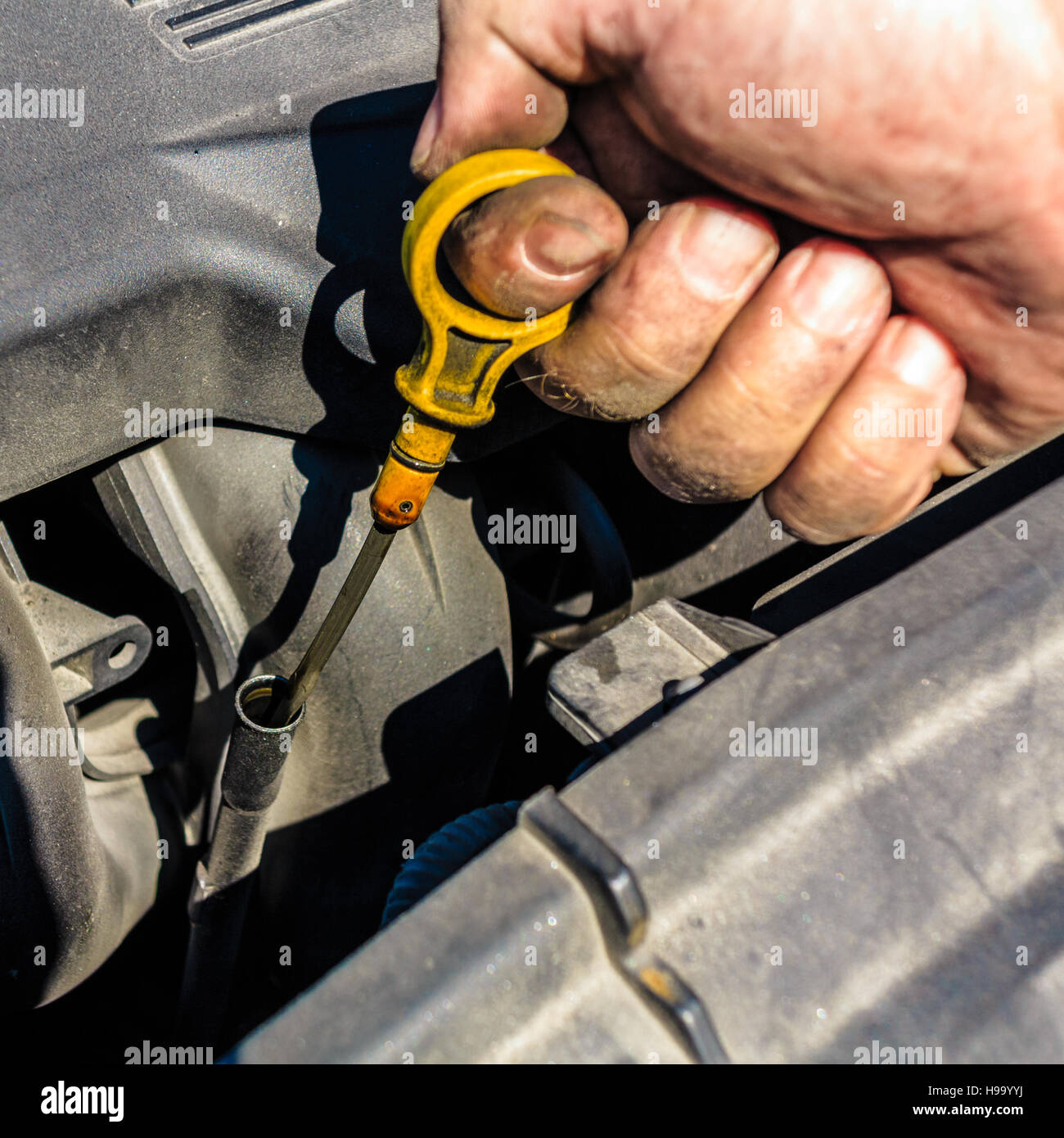 An auto mechanic checks the oil level in a car engine during routine