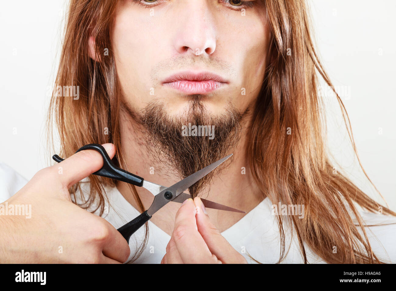 Cut and shave concept. Young man with long beard holding scissors. Part
