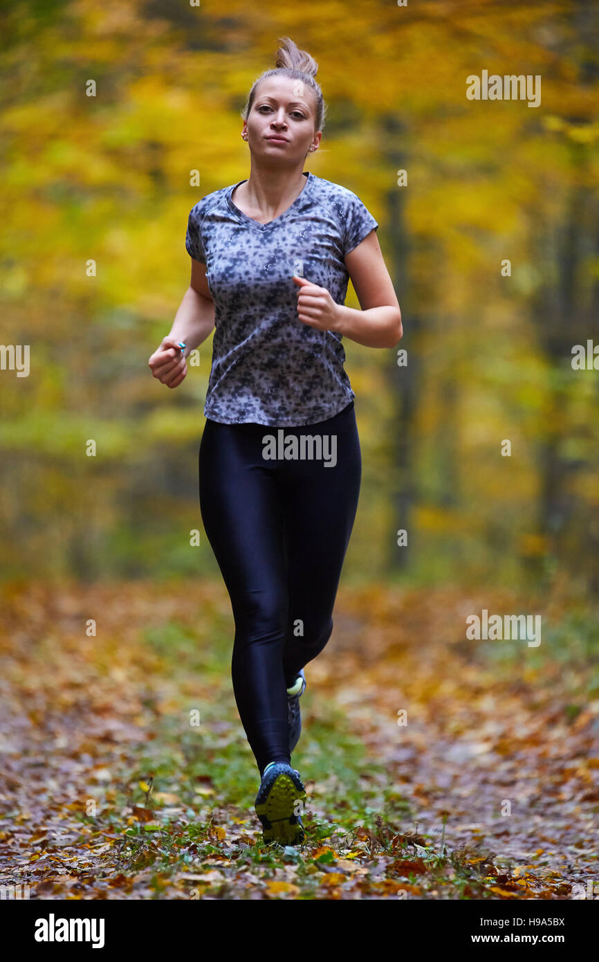 Young woman trail running through forest in the autumn Stock Photo - Alamy