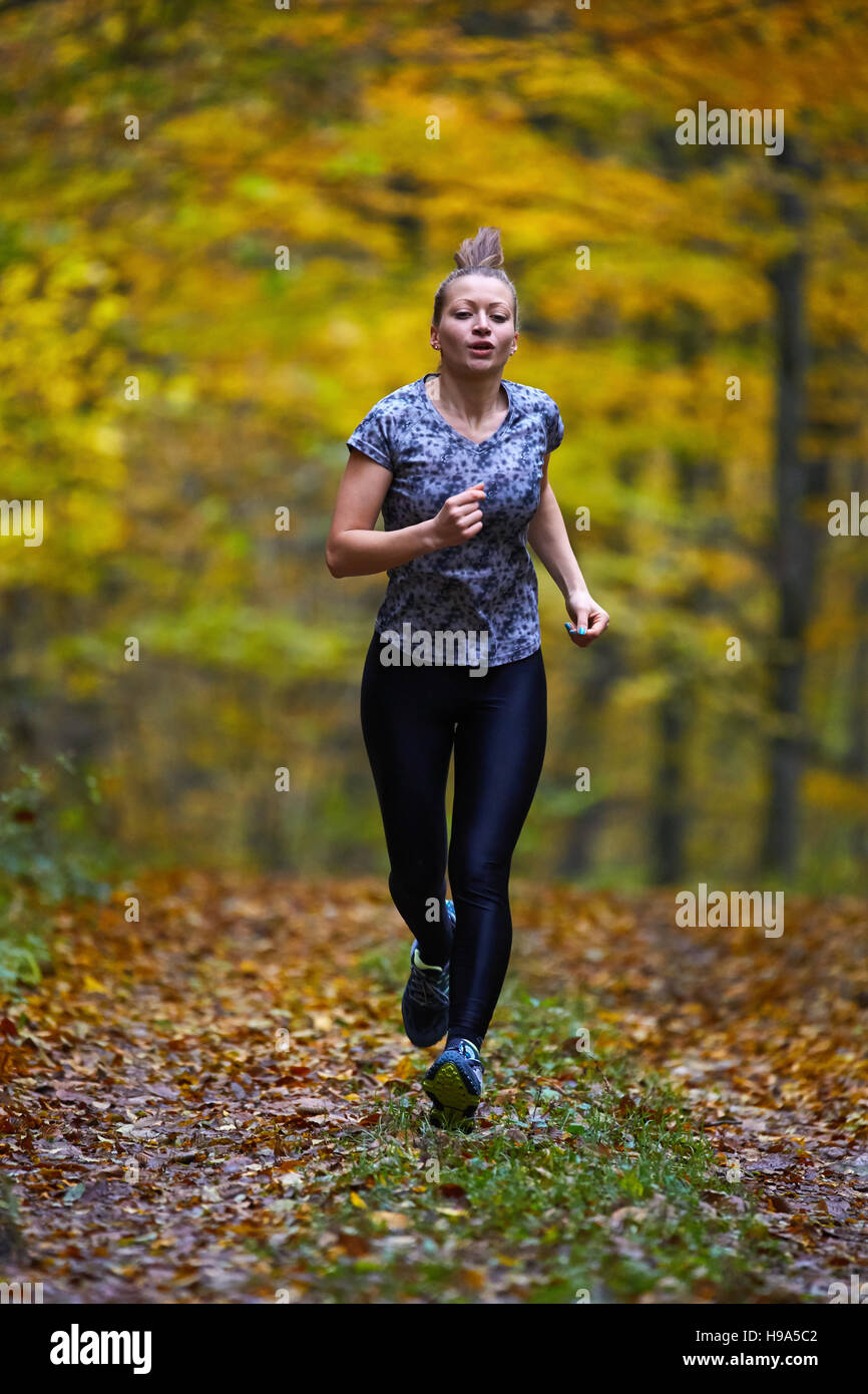 Young woman trail running through forest in the autumn Stock Photo - Alamy