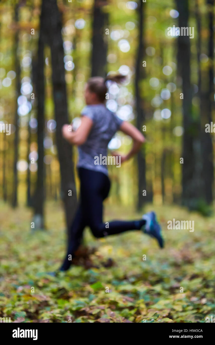 Young woman trail running through forest in the autumn Stock Photo - Alamy