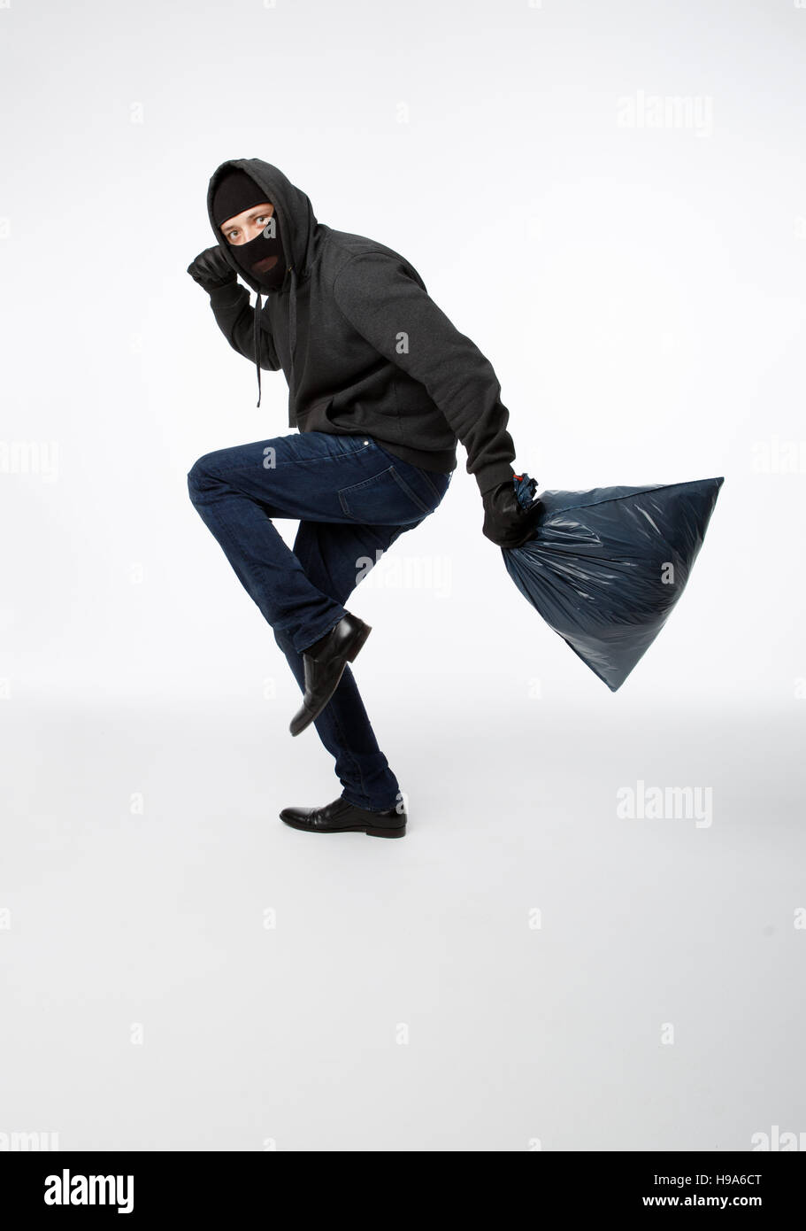 Thief slinking in black mask Stock Photo - Alamy
