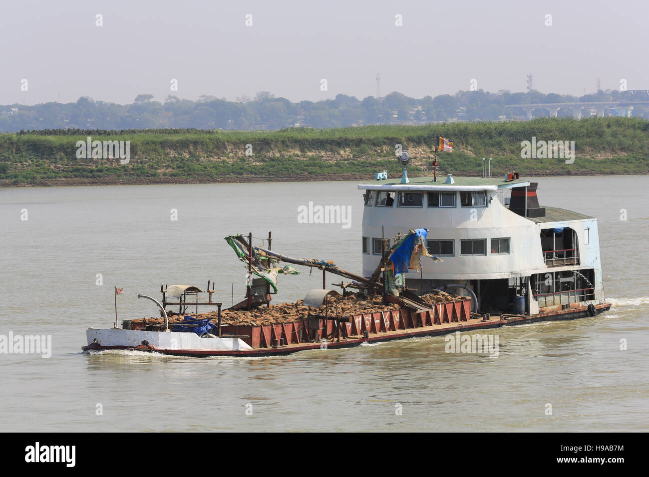 A river dredge boat heads upstream on the Irrawaddy River in Myanmar