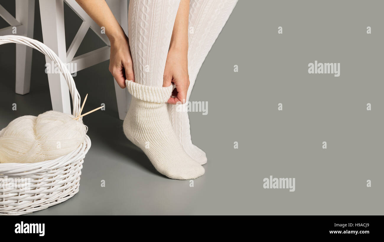 Female feet in white knitted stockings and socks near the basket with