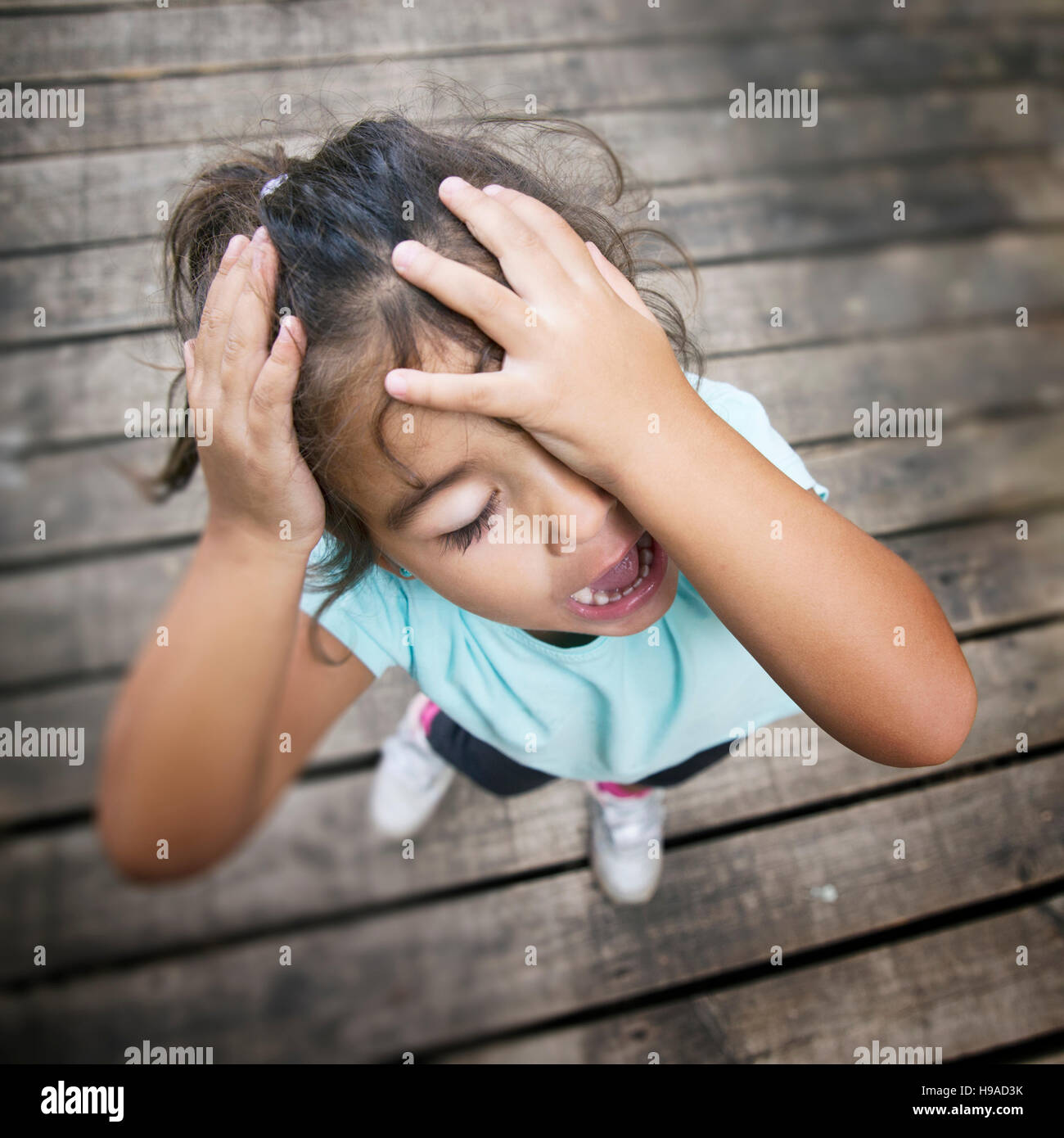 Shouting girl with eyes closed holding her head Stock Photo - Alamy