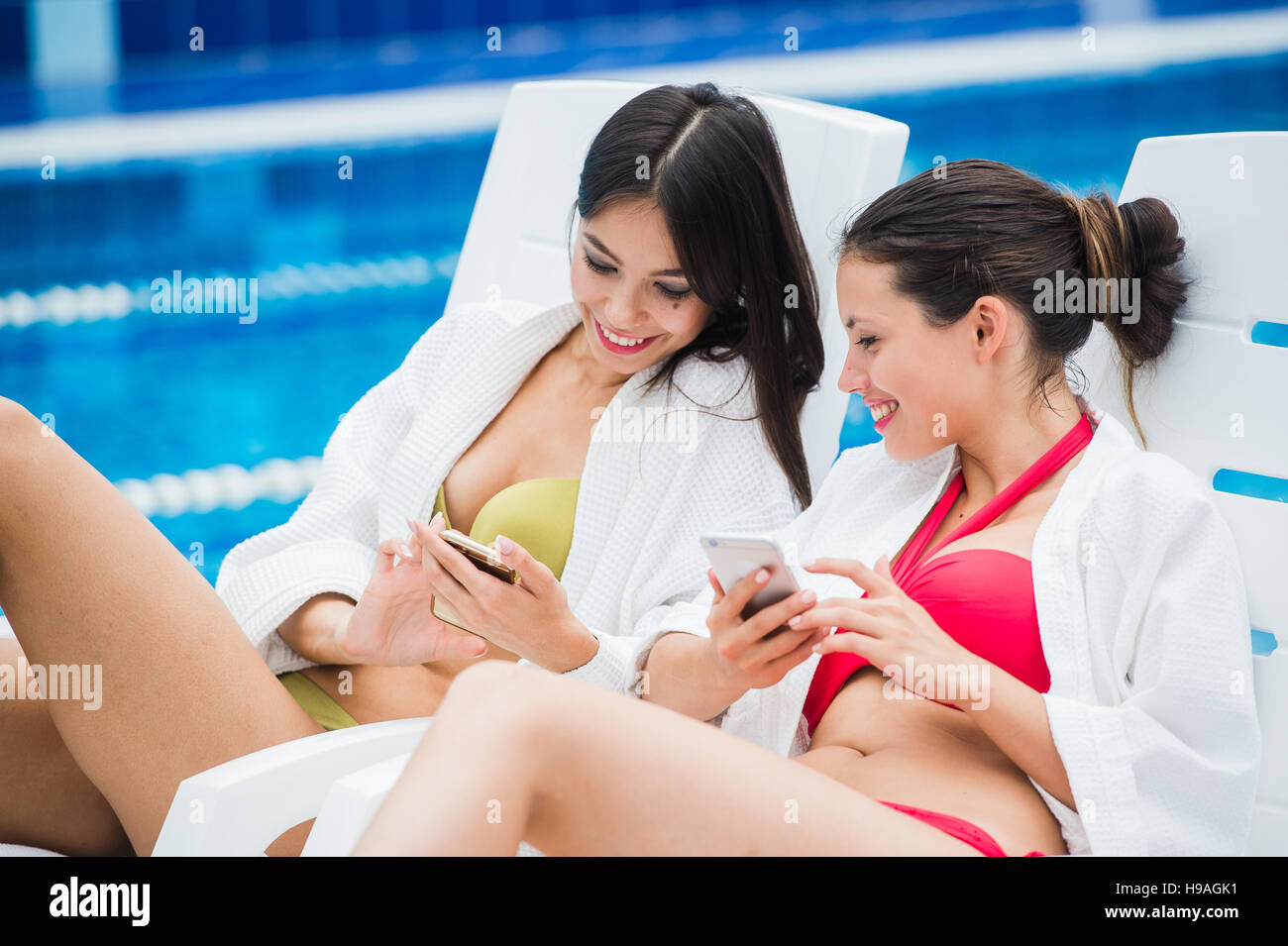 Young girls friends messaging with friend on her smartphone. Relaxation spa and technology social networks concept. Stock Photo