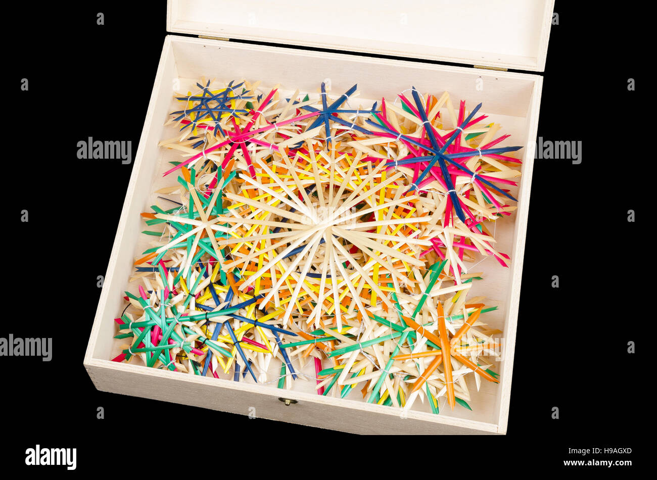 Straw stars in wooden box. Handmade colorful Christmas decoration for windows, as gifts or to hang on the xmas tree. Stock Photo