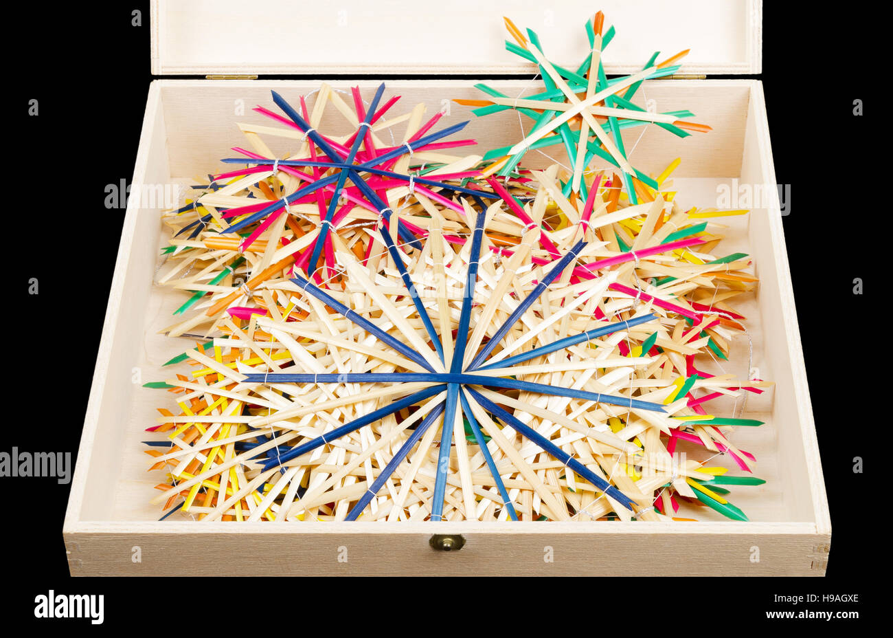 Straw stars Christmas decoration in wooden box. Handmade colorful decor for windows, as gifts or to hang on the xmas tree. Stock Photo