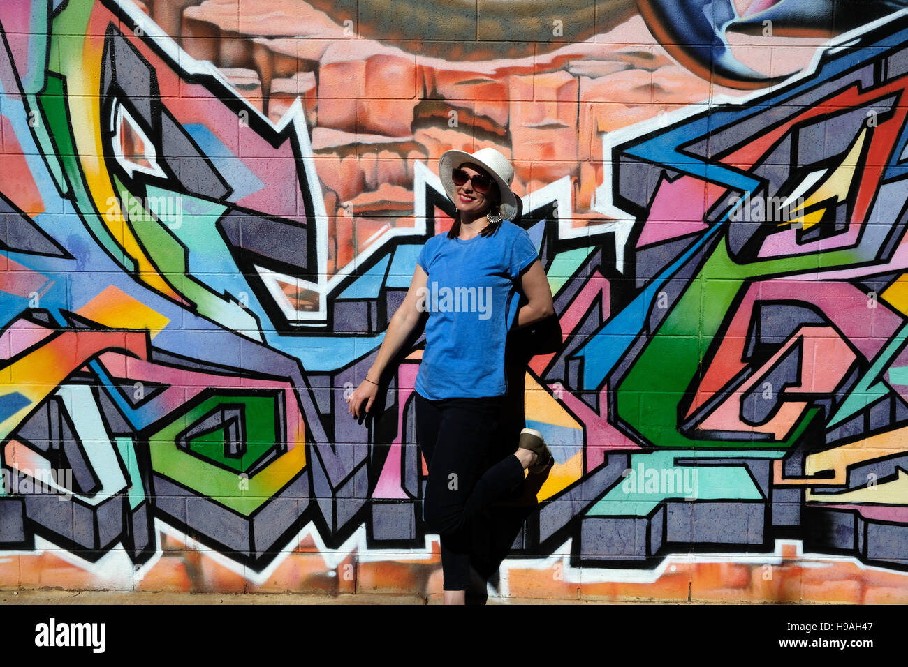 A Woman stands in front of a wall of graffiti in Alice Springs, Northern Territory, Central Australia Stock Photo