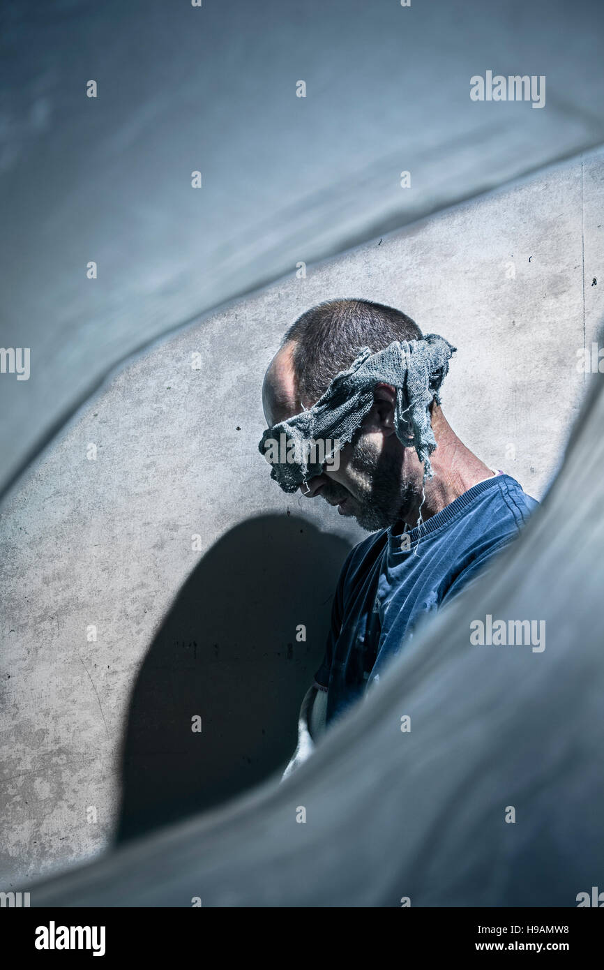 Male hostage seen through a hole in plastic sheet. Stock Photo