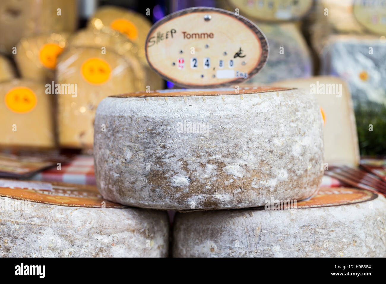Large rounds of alpine cheese with rind, displayed at farmers market stall Stock Photo