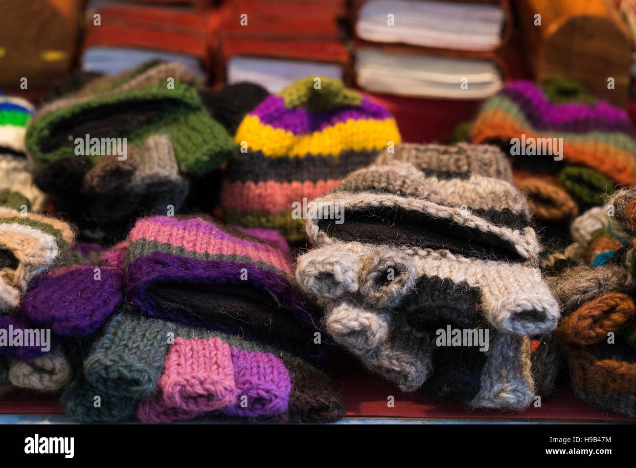 Piles of handmade wool fingerless stripe glove mittens displayed on a stall at a craft artisanal market Stock Photo