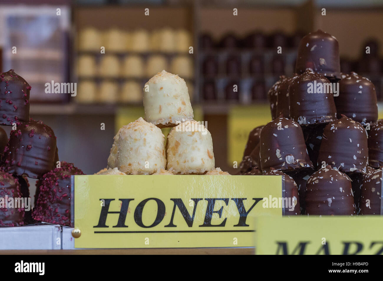 Shop market stall display of hand made artisan chocolates piled high, with honey and marzipan signs Stock Photo