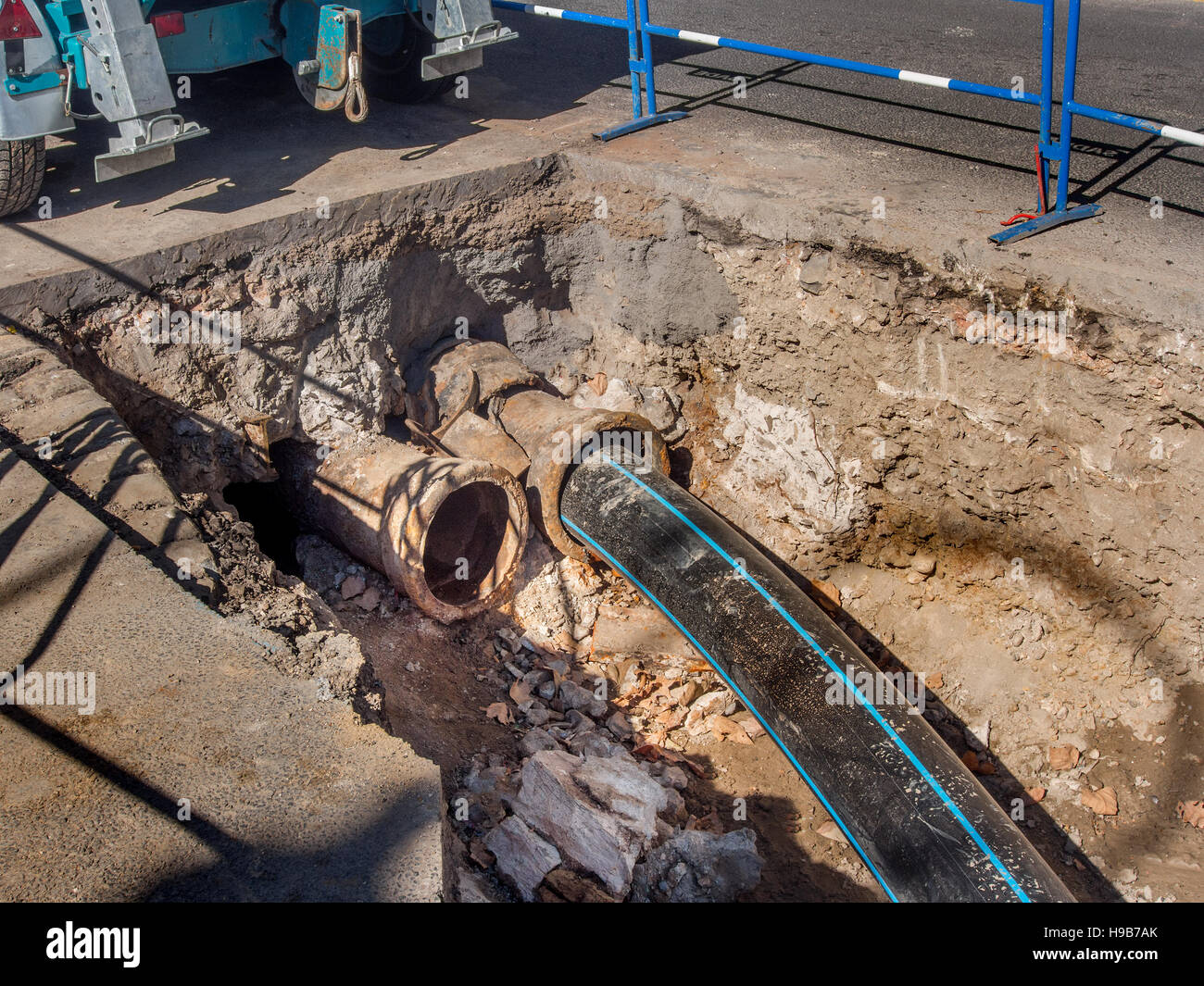 New plastic sewer pipe being inserted into a broken cast iron pipe. Stock Photo
