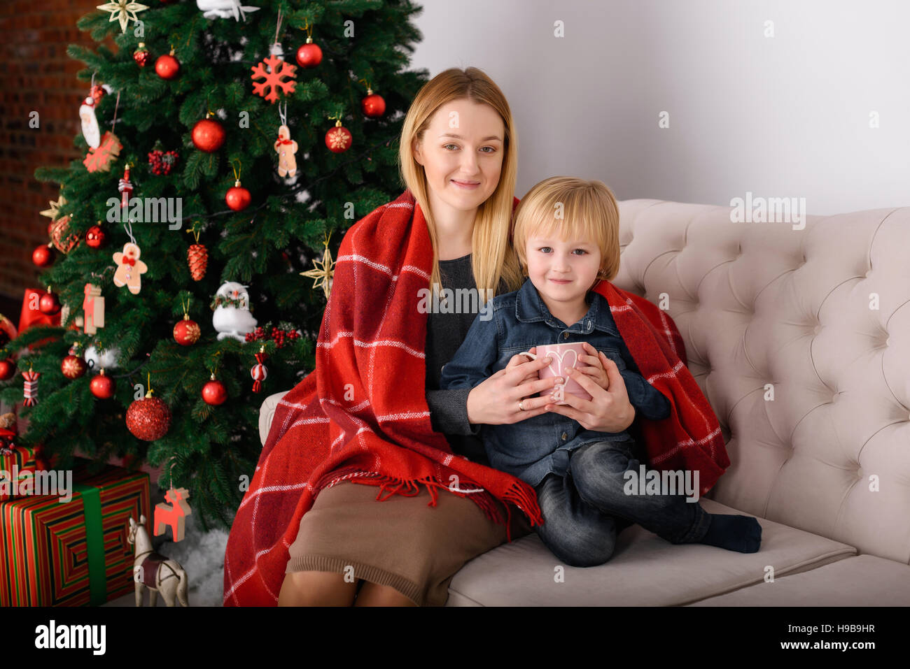 Mother and son sitting near a rug covered trees Stock Photo