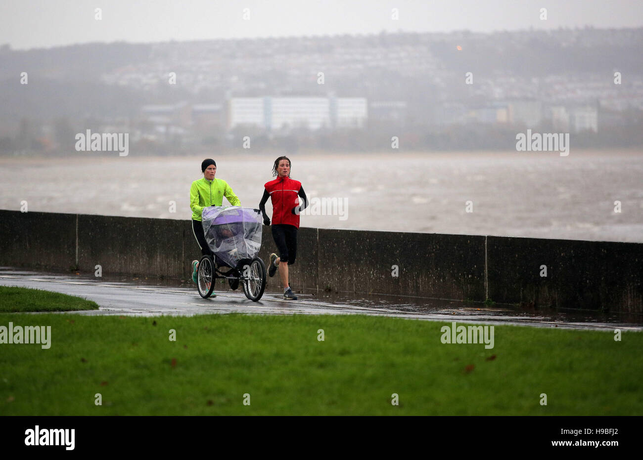 Swansea, UK. Monday 21 November 2016 Two women with a baby buggy jog by