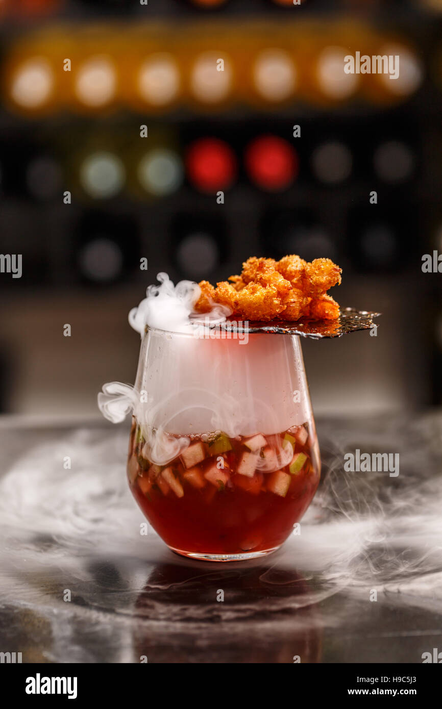 Gourmet smoking fruit soup with shrimp popcorn served on dry ice Stock Photo