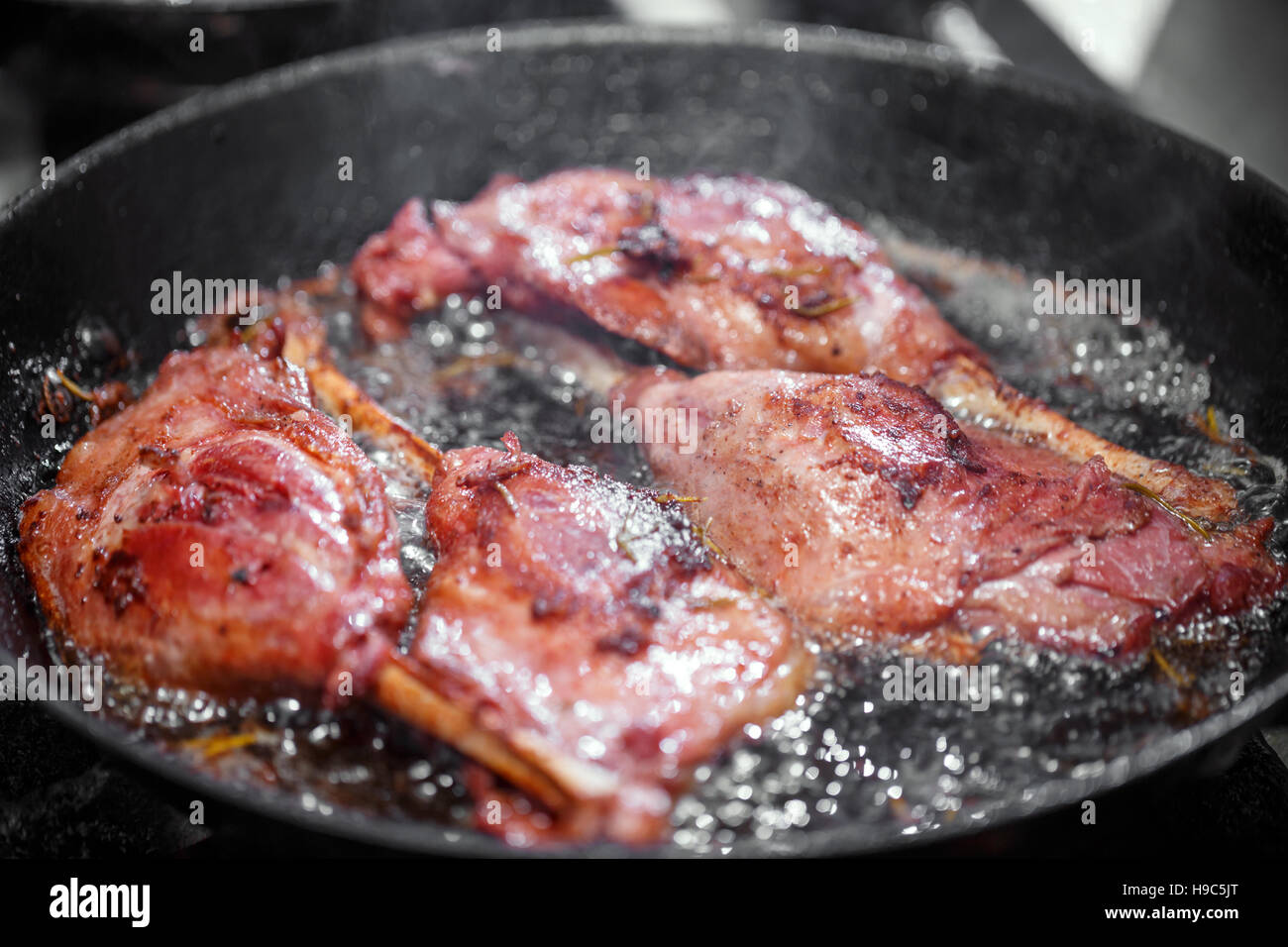 Goose drumstick frying in a pan, restaurant kitchen Stock Photo