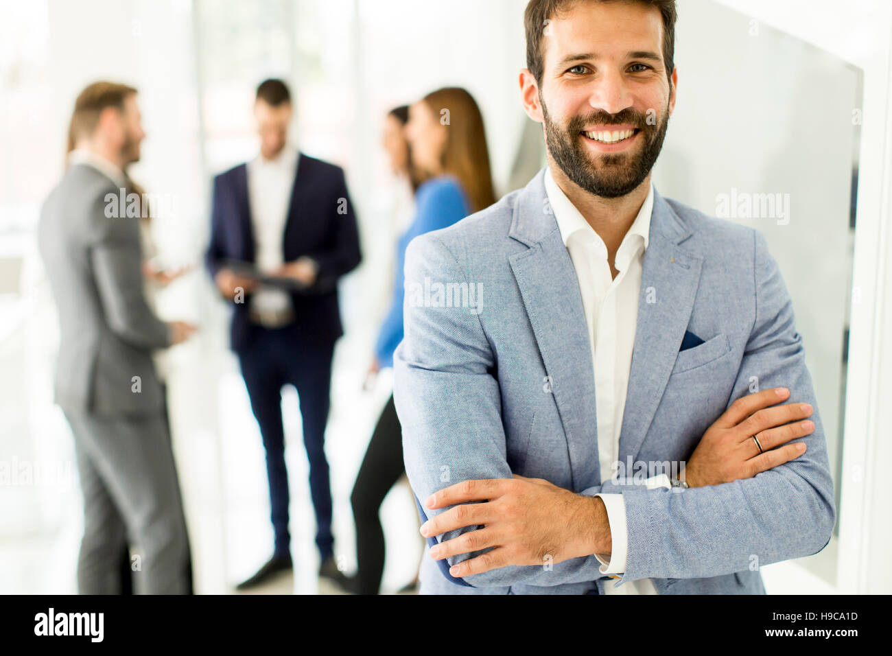 Young businessman standing in the office and other young business ...