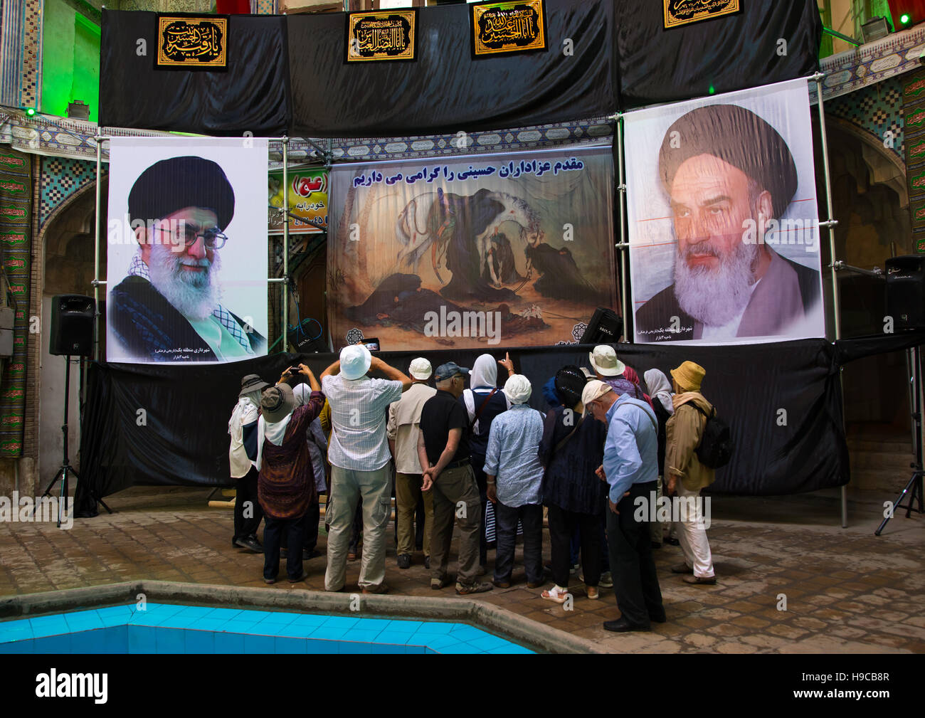 Tourists in front of khameini and khomeini posters in the bazar, Isfahan province, Kashan, Iran Stock Photo