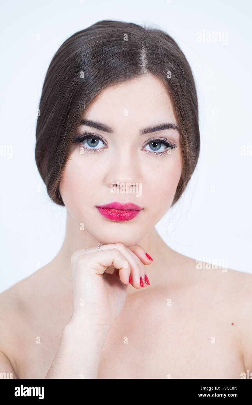 Beautiful Young Woman with Fresh Clean Skin touch own face. Red lips, red lipstick. Cosmetology, beauty and spa. Stock Photo