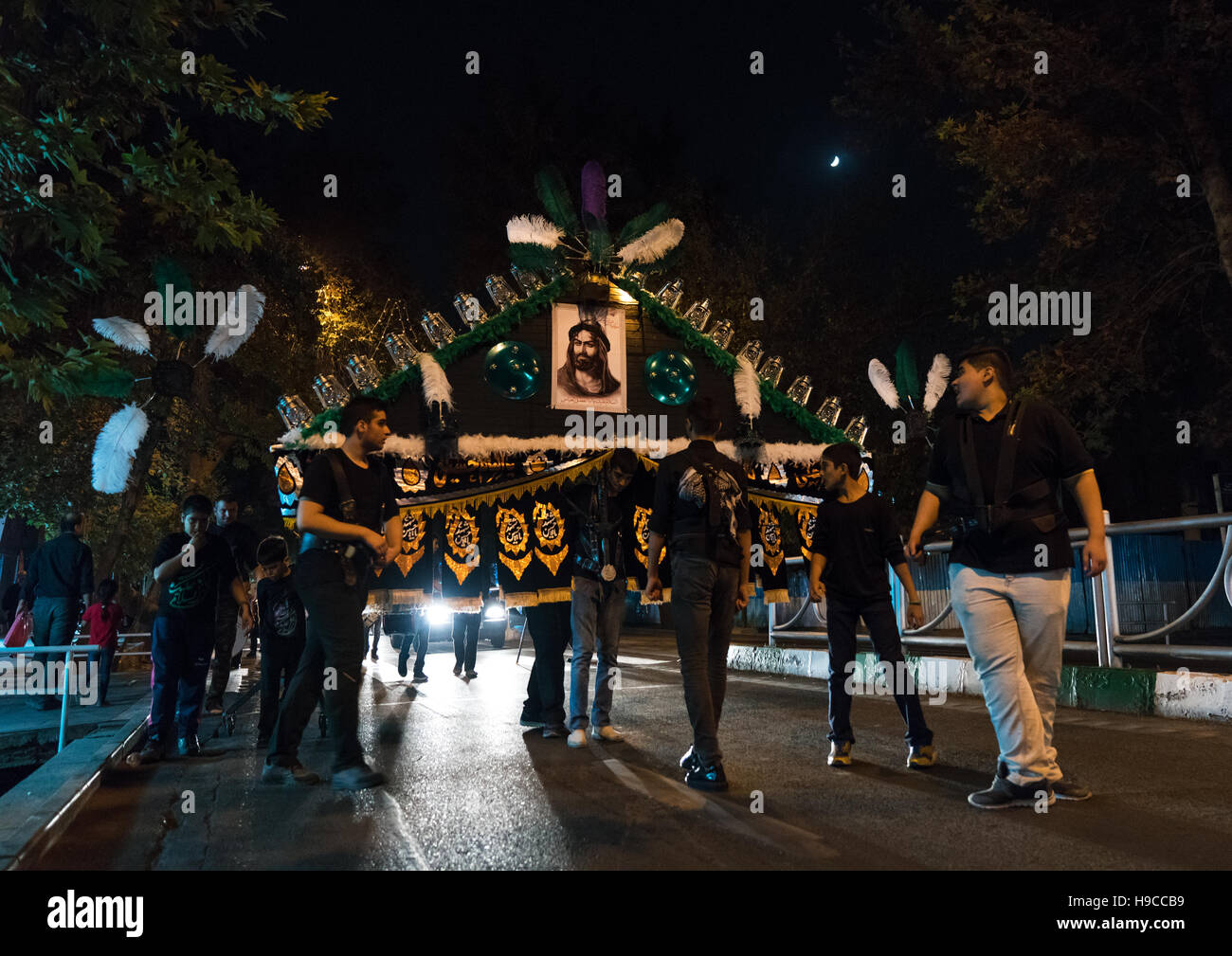 An iranian man carrying an alam is helped by shiite muslim mourners to keep his balance during muharram, Central county, Theran, Iran Stock Photo