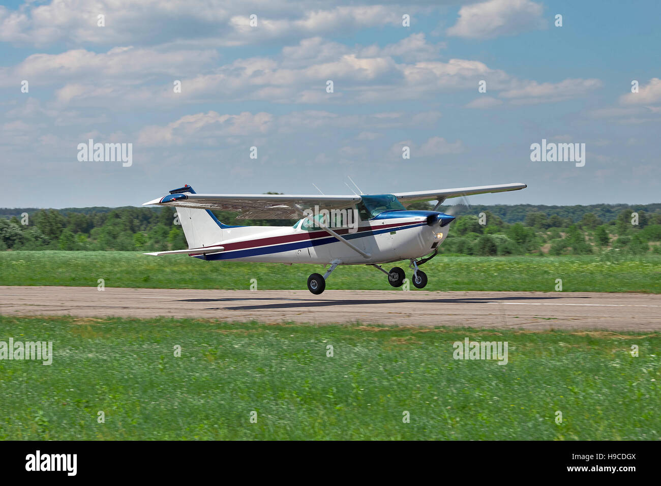 Light private plane is taking off from the runway of a small airfield on a sunny summer day Stock Photo