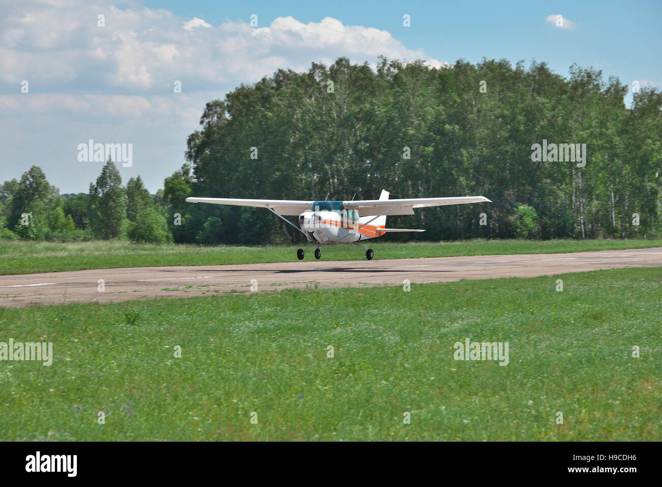 Light private plane is landing to the runway of a small airfield on a sunny summer day Stock Photo