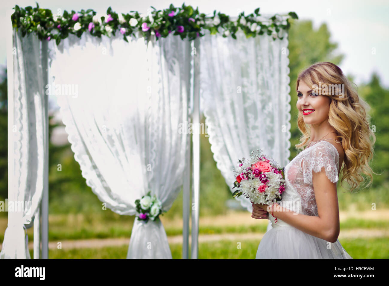 Beautiful blond bride in a white wedding dress standing in front of the ...