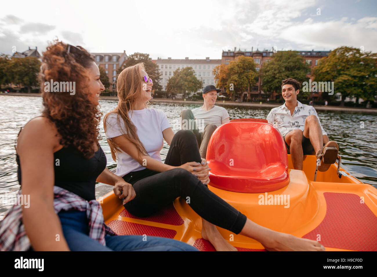 Shot of group of young people sitting on pedal boat in lake. Teenage friends enjoying on pedal boat in lake. Stock Photo