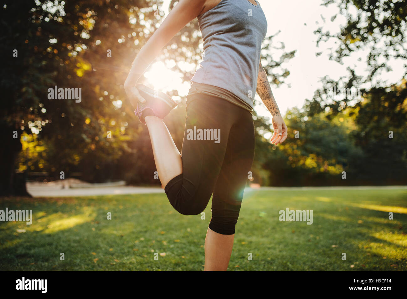 Cropped shot of fit young woman stretching legs in the park. Female exercising in the morning at city park. Stock Photo