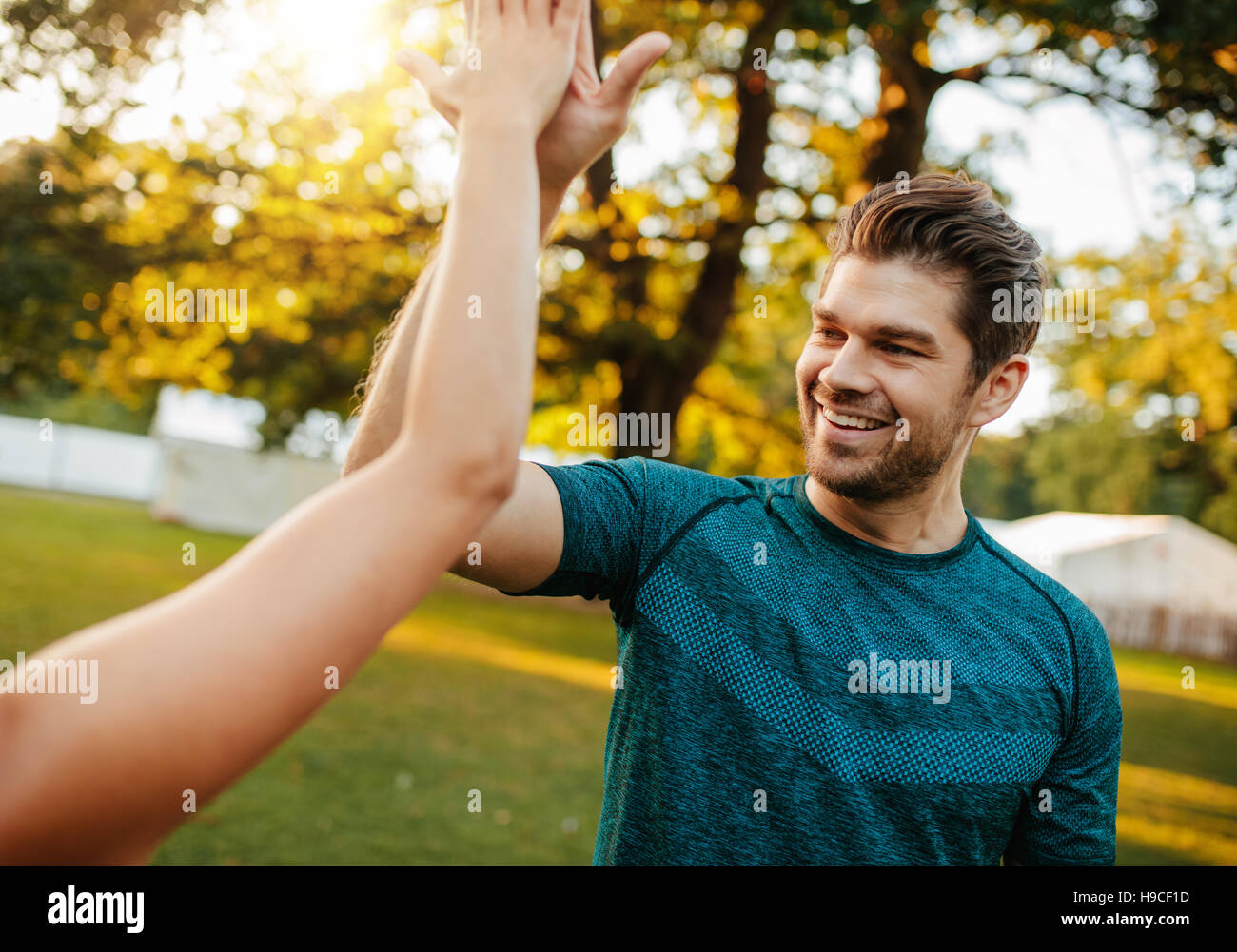 Outdoor shot of young man giving high five to a woman. fitness couple giving high five in park. Stock Photo