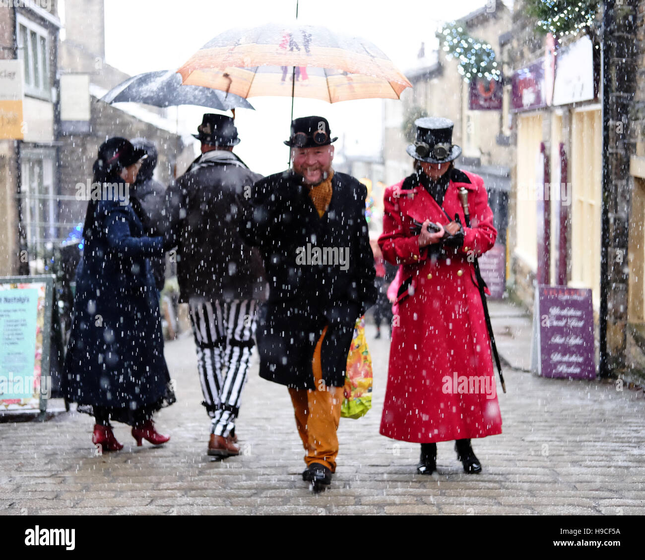 A group of people in steampunk clothing on a cobbled street in the snow with umbrellas. Stock Photo