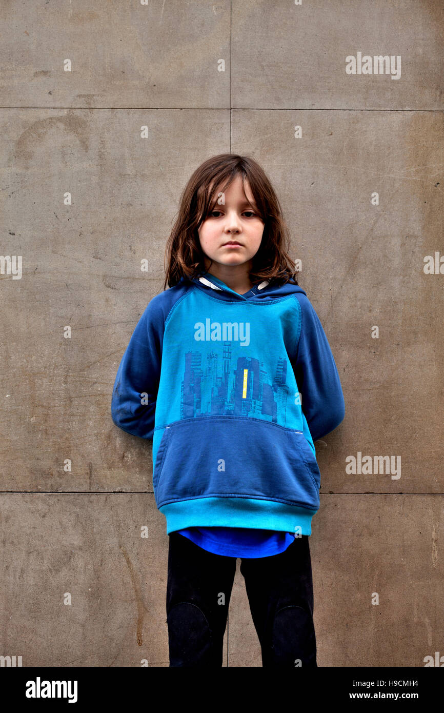 Androgynous 7 year old boy standing by wall. Stock Photo