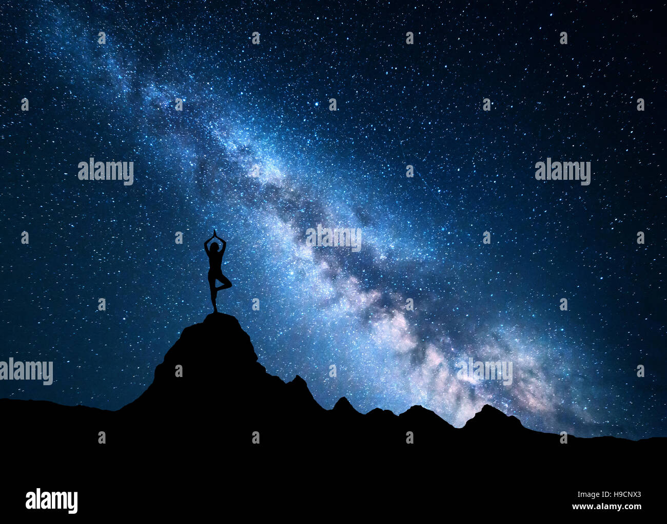 Milky Way with silhouette of a standing woman practicing yoga on the ...